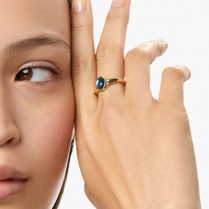 Nahaufnahme eines Vintage-Goldrings mit ovalem blauem Edelstein am Finger
