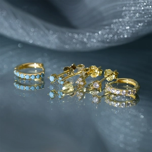 Detail van gouden S925 zilveren oorbellen set met turkoois en zirkonia edelstenen