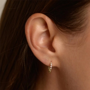Close-up of a mini gold s925 silver hoop earring with paved sparkling zircon crystals