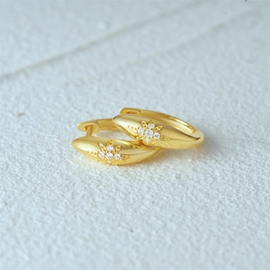 Detail view of gold S925 sterling silver hoop earrings with starburst pattern and crystals