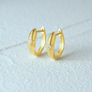 Detail of gold-plated hoop earrings featuring leaf patterns and sparkling micro-zirconia