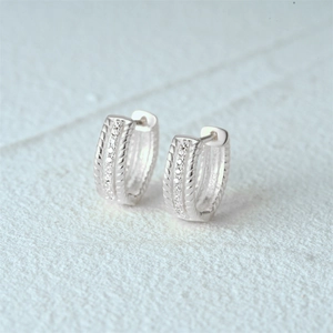 Detailed macro of S925 silver hoop earrings with triple rows of pavé zircons and rope twist