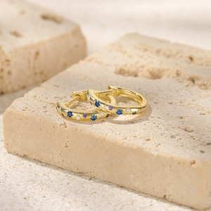 Close-up of gold s925 silver hoop earrings with blue and purple star-themed zircon inlay