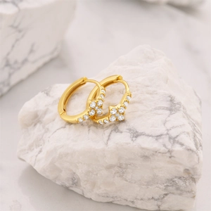 Macro detail of gold hoop earrings with sparkling starburst zircon flower clusters