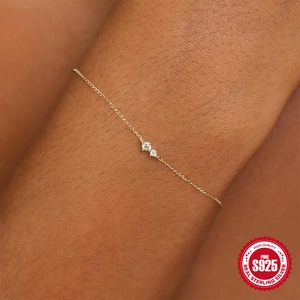 Close-up of minimalist S925 sterling silver gold bracelet with two sparkling zircons