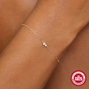 Macro detail of gold S925 sterling silver chain with two clear round cubic zirconia stones