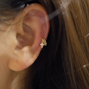 Primer plano de pendiente ear cuff de plata S925 con cadena dorada y dije de cruz