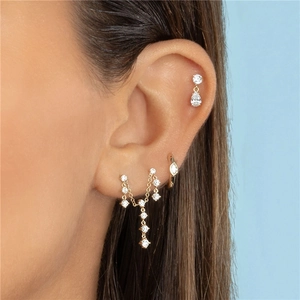 Primer plano de aretes de daga dorados con perlas de concha y malaquita en modelo