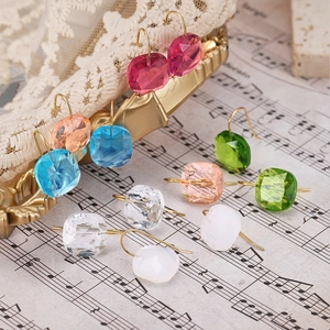 Dettaglio di orecchini a goccia in cristallo multicolore su spartiti musicali vintage eleganti