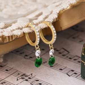 Detalle de pendientes de plata con esmeralda, circonitas blancas y acabado dorado