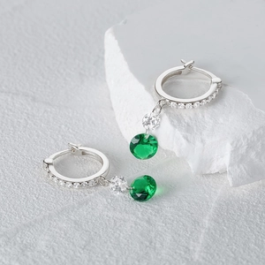 Detalle de pendientes de aro en plata S925 con circonitas verde esmeralda y cristales