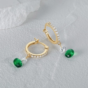 Detalle de pendientes de plata dorada con gemas verde esmeralda y circonitas blancas
