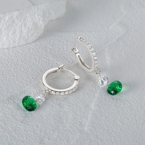 Primer plano de aros de plata S925 con circonitas blancas y colgantes de esmeralda verde