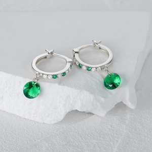 Primer plano de pendientes de aro de plata S925 con gemas esmeralda y micro-diamantes