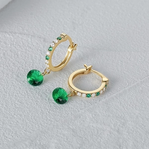 Vista macro de pendientes de aro en oro de 18K con esmeraldas y circonitas brillantes