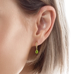 Detalle macro de pendientes de plata dorada con piedras de esmeralda con corte de pera