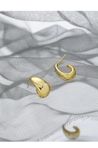 Macro shot of minimalist gold S925 silver oval stud earrings with a high-polished mirror finish