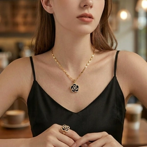 Elegant camellia necklace and ring set with black petals and gold-plated edges on model