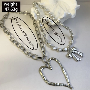 Close-up of layered silver chain necklace with heart pendant and pearl bow details