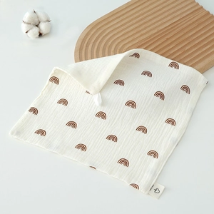 Macro detail of white cotton gauze baby towel featuring brown rainbow print and hanging loop