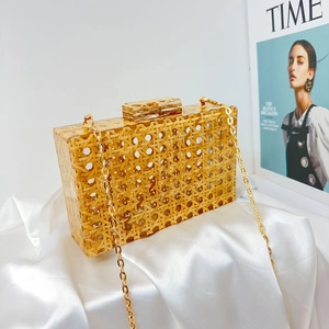 Detail of yellow acrylic evening clutch with woven texture and golden chain strap