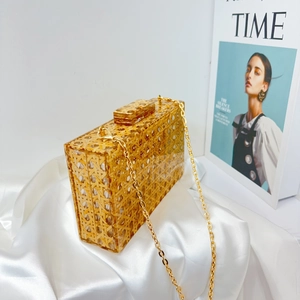 Detail of vintage woven texture acrylic clutch bag with a golden chain on white satin