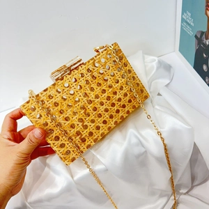 Detail of vintage woven rattan acrylic clutch bag with golden chain and block clasp
