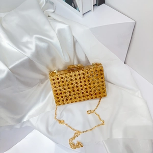 Detail of gold woven acrylic clutch bag with a detachable metal chain on white satin