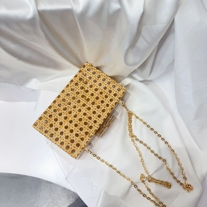 Detail of vintage acrylic clutch with woven straw texture and gold chain strap