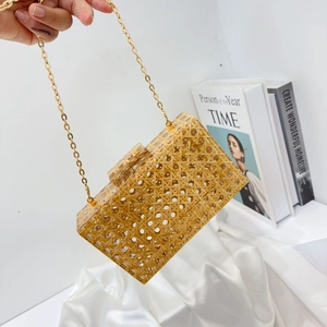 Detail of square acrylic clutch with woven texture and gold chain strap for party
