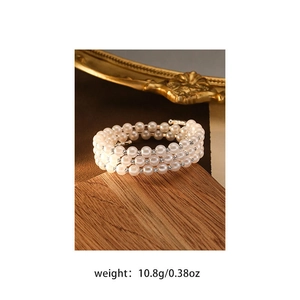 Detail of three-layer pearl bracelet with sparkling silver spacers on wood base