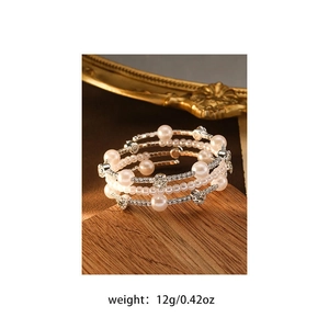 Detail of multi-layer spiral bracelet with pink pearls and zircon on a wooden stand