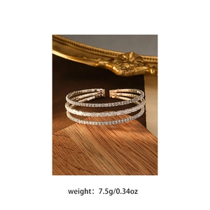 Detailed close-up of a triple-layer gold bracelet featuring baguette and round-cut zircons