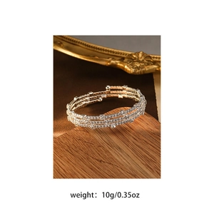 Close-up of a three-layer silver spiral bracelet with clear pavé crystals on wood