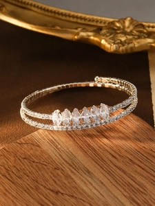 Detail of silver double-layer bracelet featuring marquise-cut zircons on a wooden stand