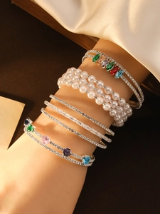 Detail of layered bracelets featuring pearls, colorful zircon stones and silver-plated finish