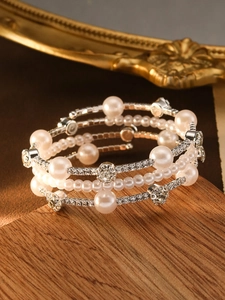 Detail of multilayer wrap bracelet with white pearls and sparkling zircons on wood