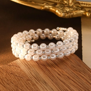 Luxury multi-layer pearl bracelet with sparkling zircon spacers on a rustic wooden background