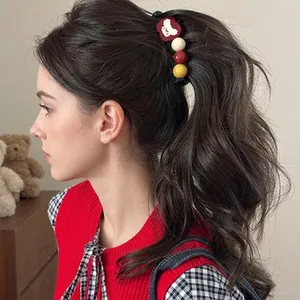 Detail of red bear heart hair clip and colorful beads styled on wavy dark hair