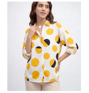 Détail de la chemise blanche à manches longues avec pois géométriques jaunes et noirs