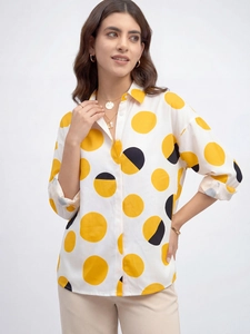 Détail de la chemise à manches longues avec de grands pois jaunes et noirs à boutons