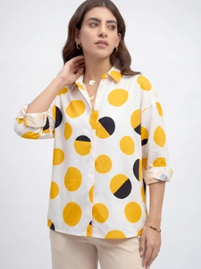 Détail de chemise blanche à grands pois jaunes avec un collier à pièces dorées chic