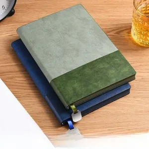 Detail of soft leather A5 notebook with silk bookmark and metal pendant on wooden desk
