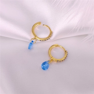 Vista macro detallada de pendientes de aro S925 dorados con gemas azules de lágrima