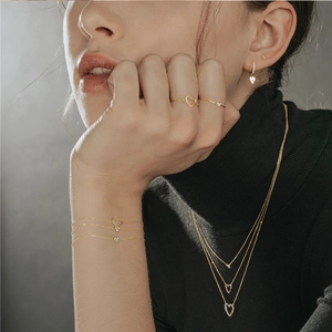 Close-up of elegant gold plated S925 silver rings and heart necklaces on a model