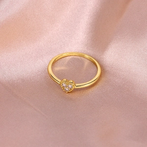 Macro view of dainty gold heart ring with three sparkling crystals on pink satin