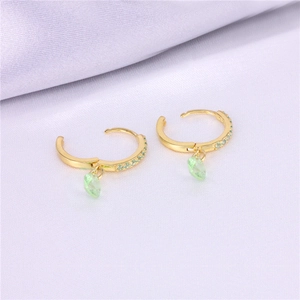 Detalle macro de los pendientes de corazón con esmeralda y oro sobre seda fina