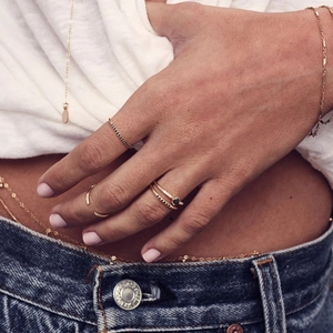 Close-up of elegant gold ring set and body chain jewelry on model in casual wear