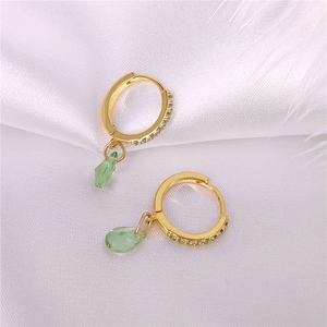 Detalle de pendientes de aro dorados con diamantes y colgantes de gota verde esmeralda