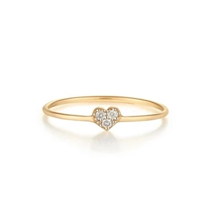 Macro shot of minimalist gold heart ring with three small diamonds on a white background